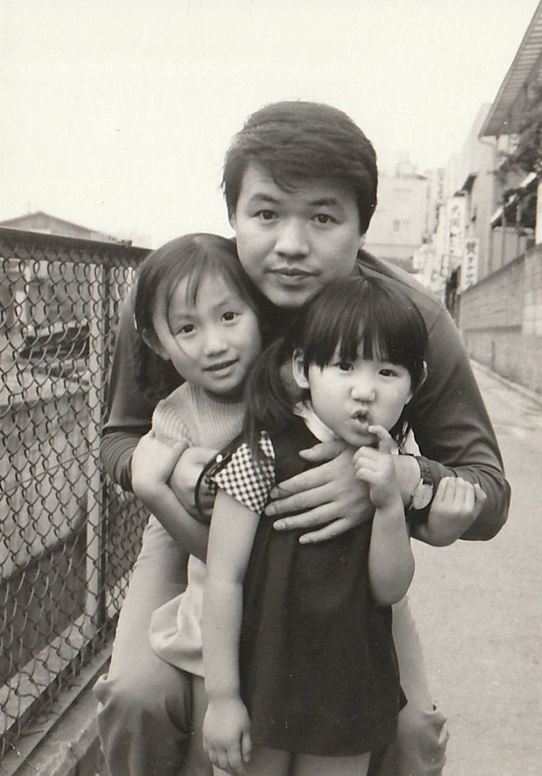 姉と一緒に父親に抱きしめられる幼少期の高橋さん（一番手前）