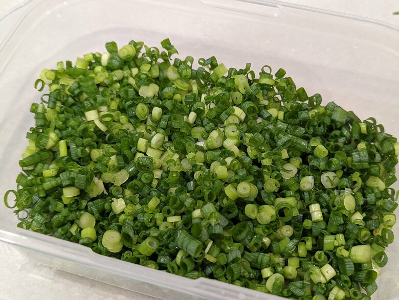 【青ねぎの冷凍保存法】1.青ねぎの小口切りを冷凍保存容器に入れる。容量いっぱいに詰めないことがポイント