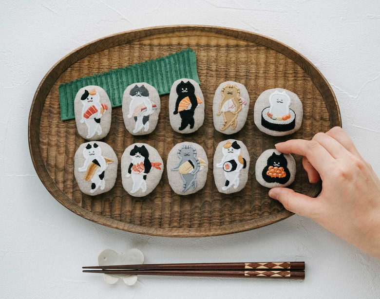 「運ぶねこ」シリーズの刺繍作品。小脇に抱えるのはなんとお寿司!?
