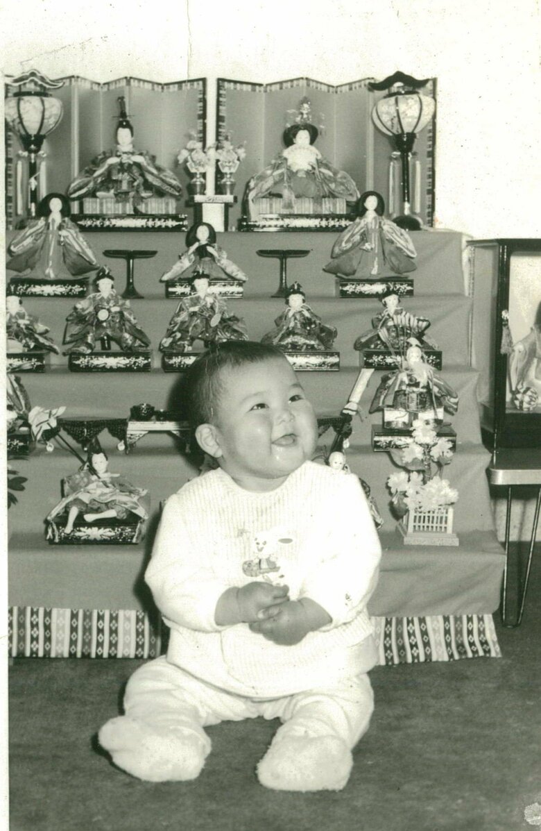 幼少期、雛人形の前でポーズ