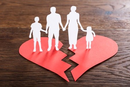 74217761 - close-up of a family paper cut on broken heart at wooden desk