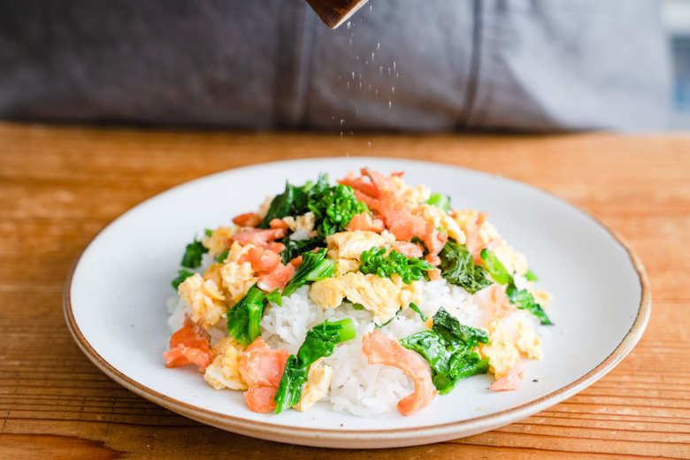 スモークサーモンと菜の花のご飯に黒こしょうをかける