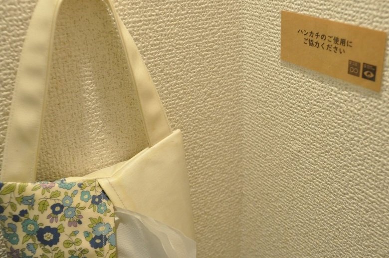 カフェの洗面所にある手拭きペーパーの横にそっと貼られた「ハンカチのご使用にご協力ください」の文字。