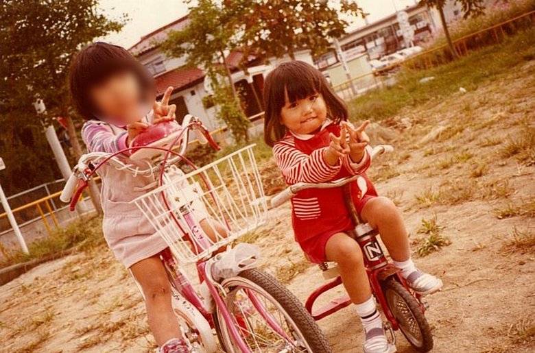 赤い洋服を着て三輪車に乗っている佐藤さん（右）