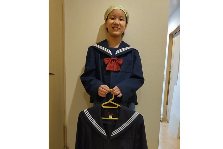 奏さんの肌に合う優しい素材で作った自作の制服を着て（手にしている制服は市販のもの）