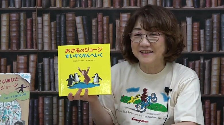 「おさるのジョージ」の可愛らしいイラストが描かれたTシャツ姿で講演をする翻訳者の福本さん