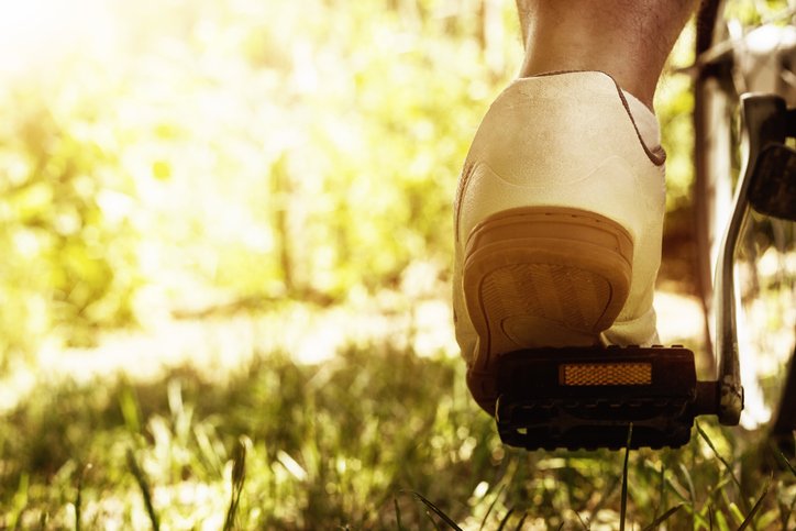 shoe on the bike pedal in front of bloomy sunny nature background