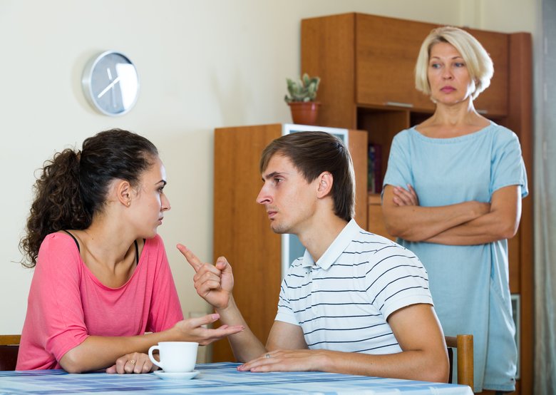 Upset female retiree watching adult kids quarrelling at home