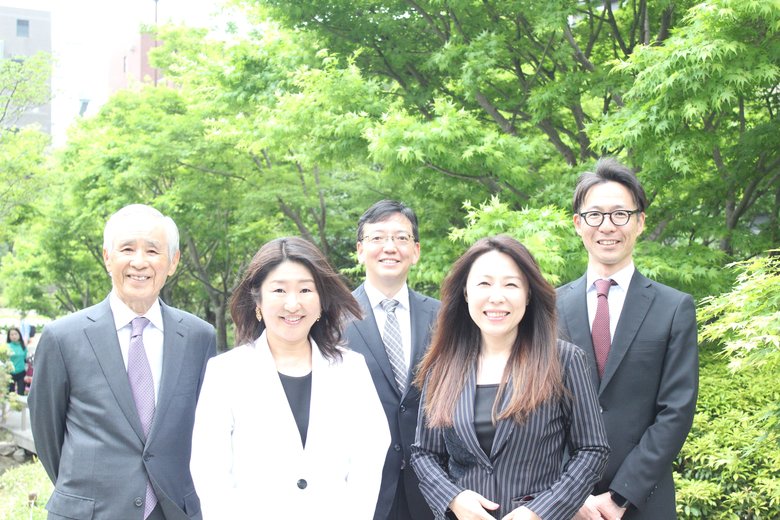 「ドコデモこども食堂」を運営する一般社団法人 明日へのチカラ 理事の集合写真。代表の岩朝さんは心強い仲間に囲まれていい笑顔（前列右）