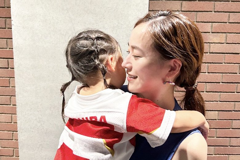 日本代表のラグビージャージを着た娘さんを抱っこする金井さん