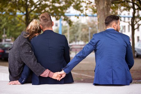 89405093 - couple sitting on bench and hugging while the woman holding hands with another man