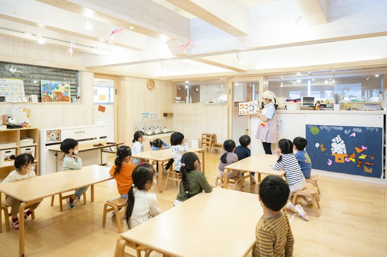 保育士が絵本の読み聞かせをしているひとコマ。真剣に耳を傾ける子どもたち