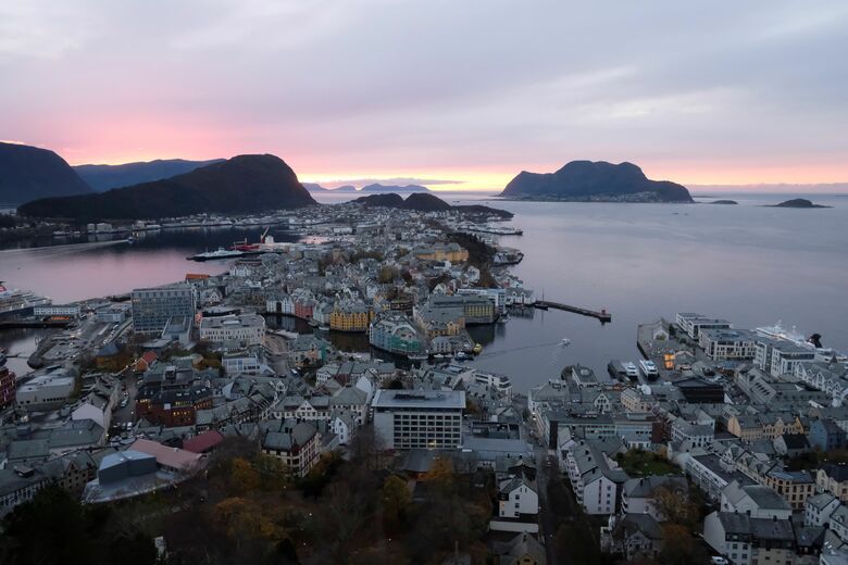 2022年11月に撮った写心。ノルウェーのオーレスンで夕焼け海と港町を見下ろし夕日のあたたかさに感謝し桃色を感じた