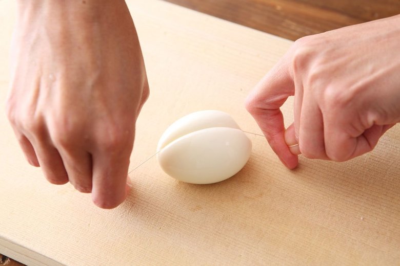 糸で半熟卵を半分に切っているところ
