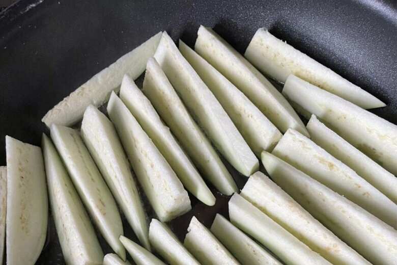 【作り方2】中火で熱したフライパンに多めの油を入れ、なすを皮目から並べて焼き、皿に盛る