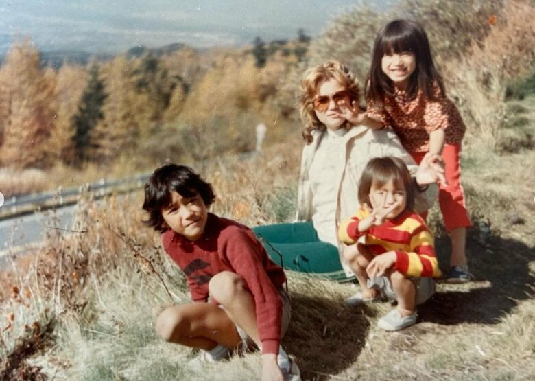 笑顔が可愛い小さい頃の佐田さん（写真右上）と金髪に巻き髪、サングラス姿がおしゃれなお母さんと兄弟との家族写真