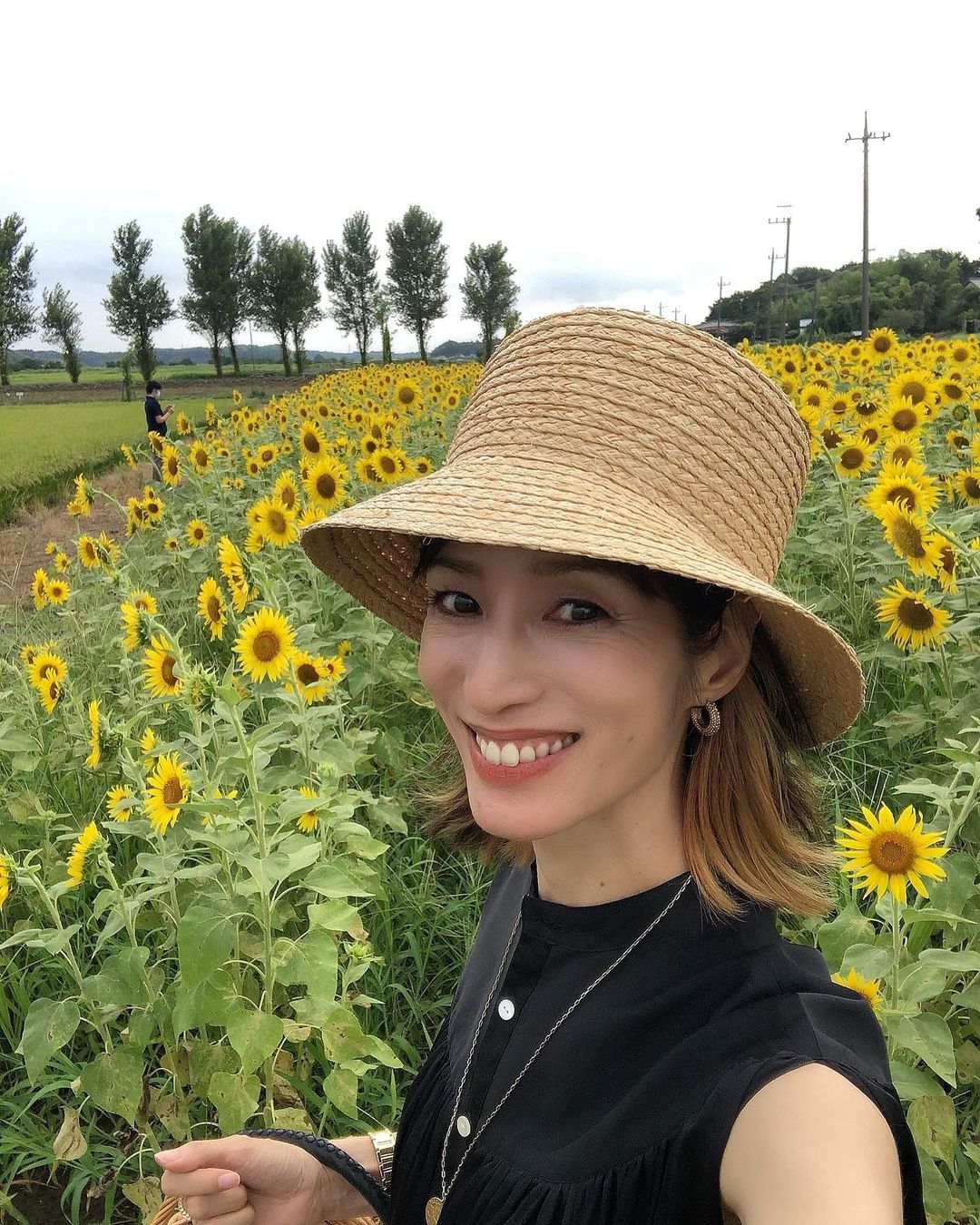 ひまわり畑を背景に笑顔を見せる佐藤さん（Instagramより）