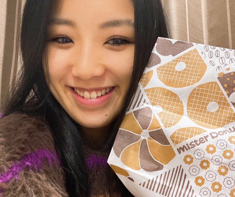 テイクアウトしたミスタードーナツの紙袋をもつ西田さん