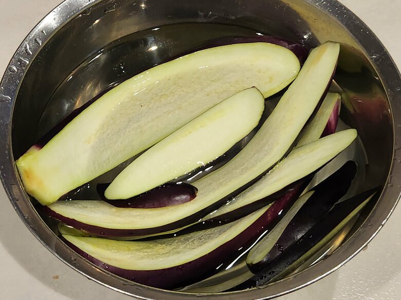 【「なすの生姜焼き丼」の作り方1】なす1本を縦に薄切りし、10分ほど水に漬けた後、水けをキッチンペーパーで取る