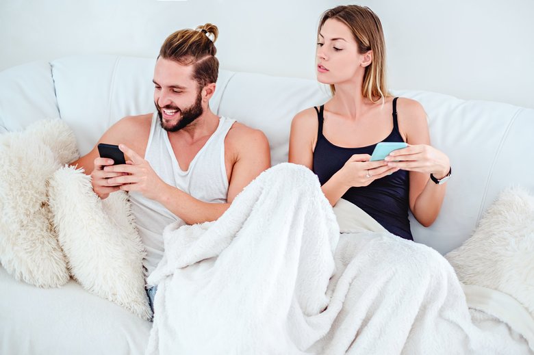 Girl looking over her boyfriend shoulder at his phone