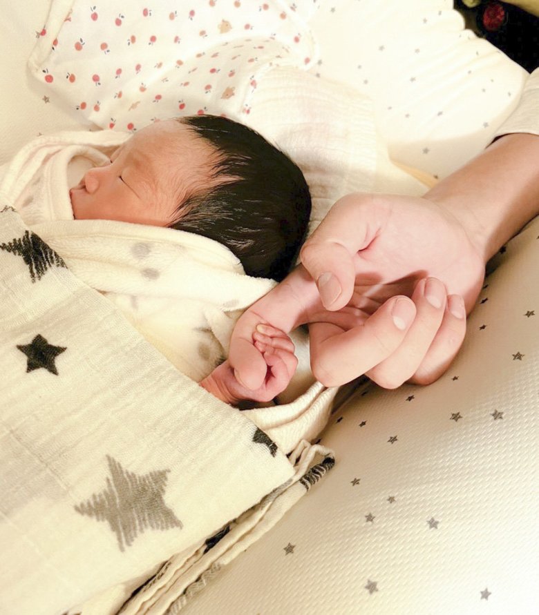 産まれたばかりの長女の手を握るハジメさん