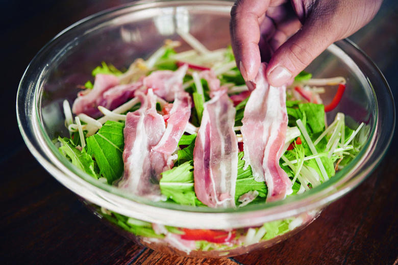 耐熱ボウルに①の野菜と豚肉を交互に積み重ね、ラップをして電子レンジ(600W)で3～4分加熱する。