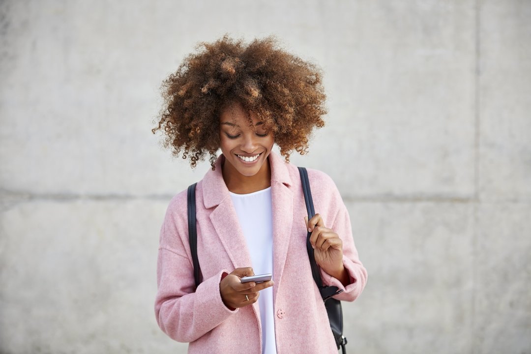 Happy woman text messaging through mobile phone