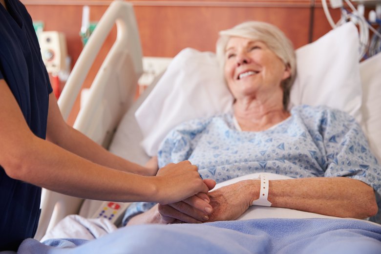 Close Up Of Hospital Nurse Holding Senior Patient's Hand