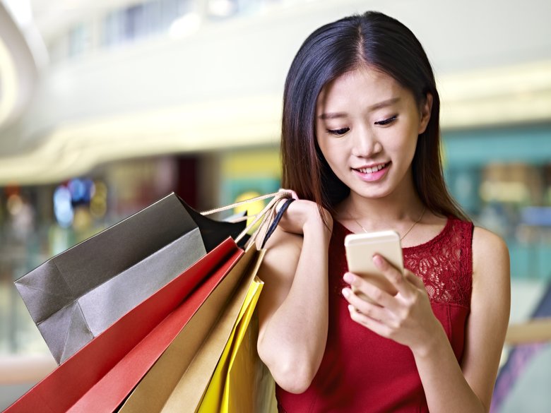 young asian woman using cellphone during shopping