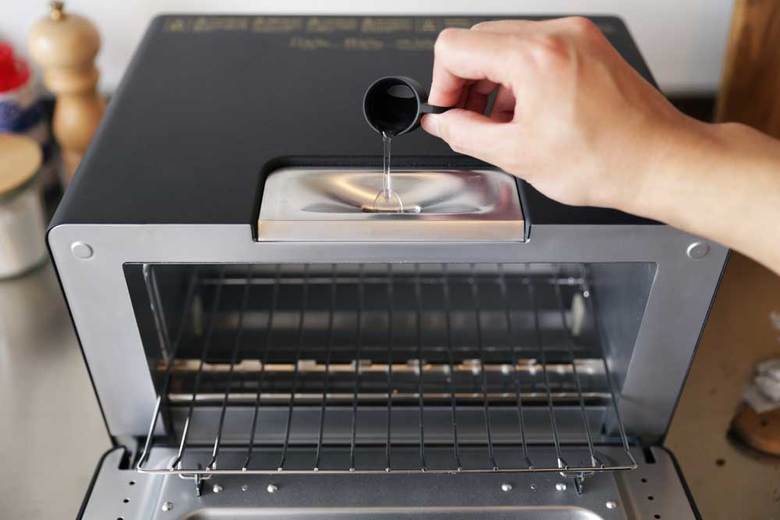 ▲枚数が違っても入れる水の分量は同じ。付属のカップを使い、トースター上部の給水口に水を入れる。連続で焼く際は、焼くたびに水を入れるのを忘れずに