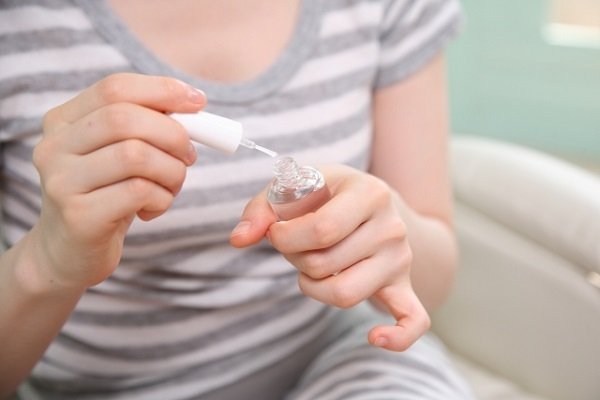 ネイルオイルを丁寧に塗る女性の画像