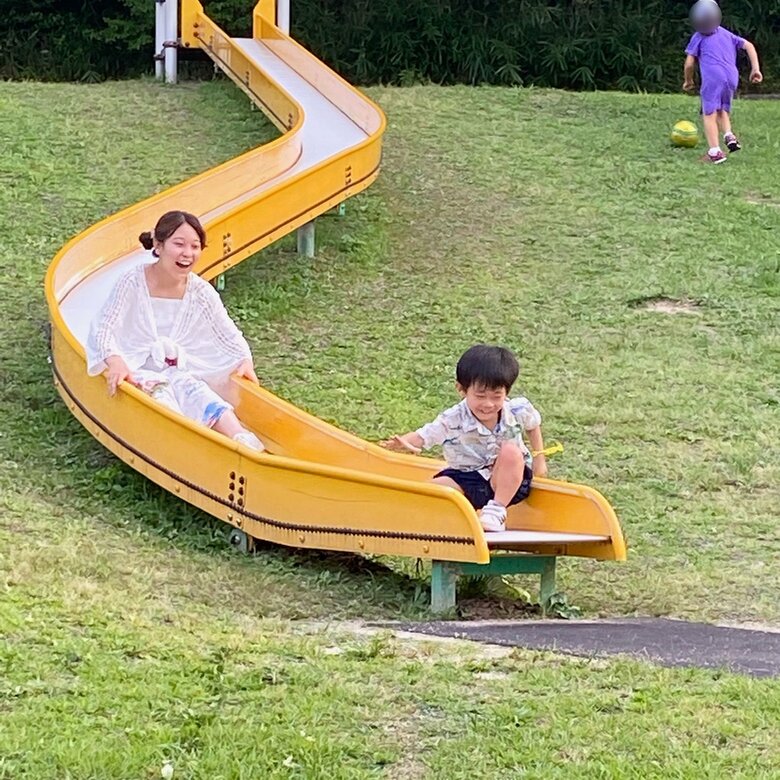大きな滑り台で笑顔で遊ぶ親子