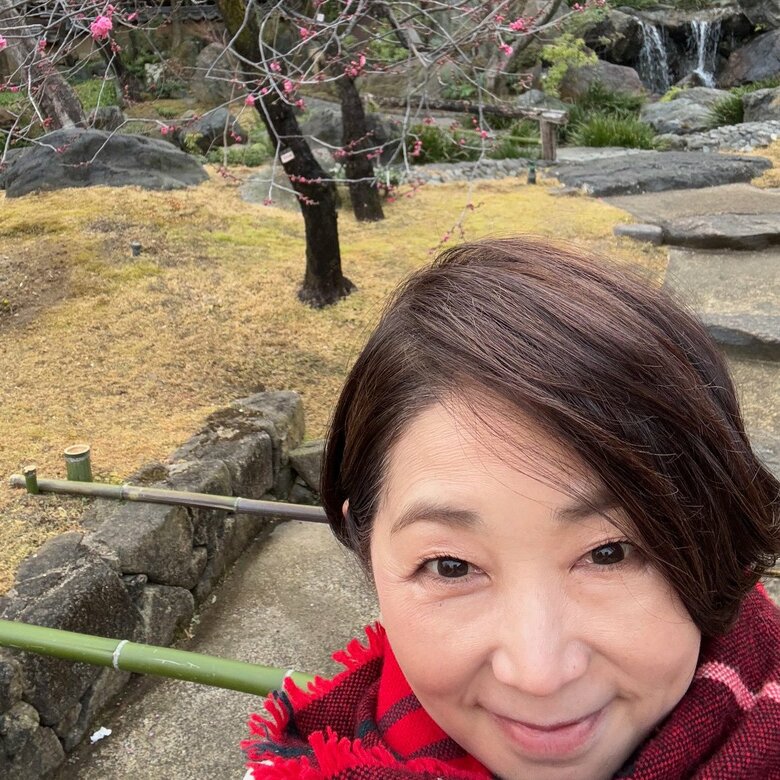 咲き始めた梅の花をバックに。中井美穂さんのプライベートショット