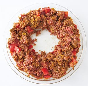 ①を、まん中をあけてドーナツ状になるよう広げる。ふんわりとラップをかけ、600Ｗの電子レンジで10分加熱する。とり出して、トマトをつぶすようによく混ぜ合わせる。