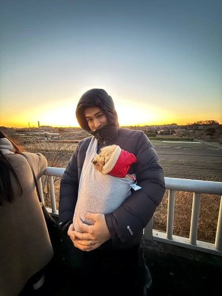 愛犬を抱いたブローハン聡さん。朝日をバックに