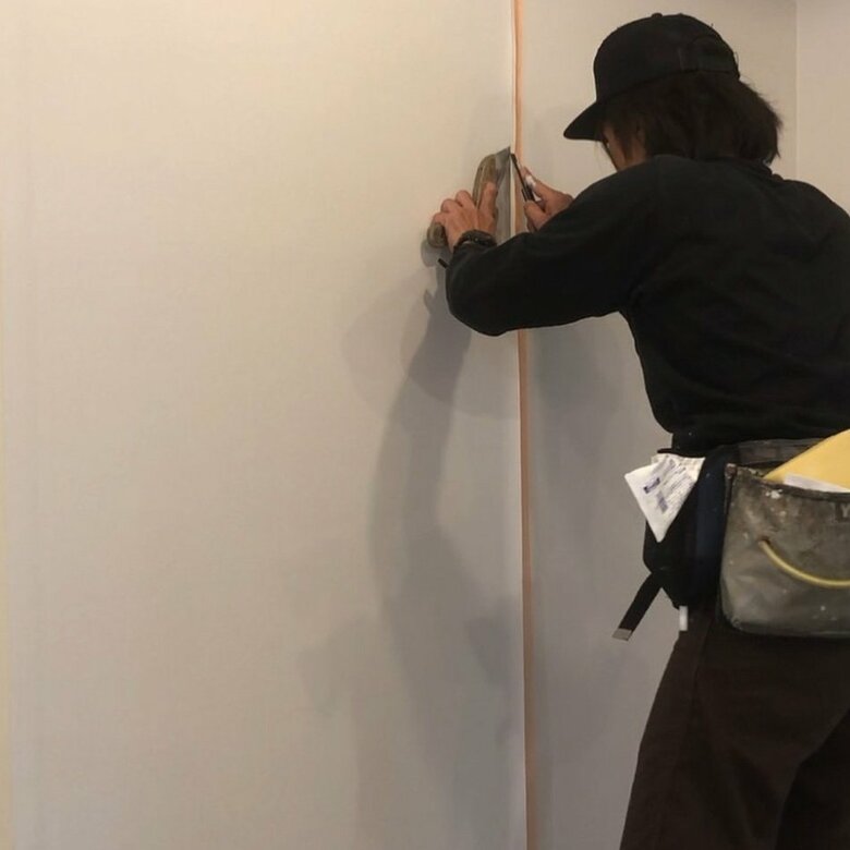 「背中で語る！」壁にクロスを貼る仕事中の斉藤慶太さん