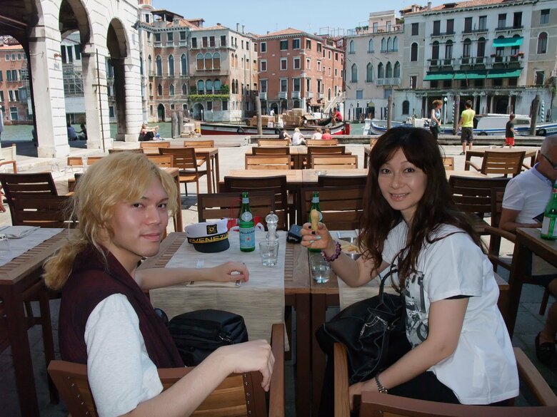 イタリアのベネチアで、運河沿いの街並みをバックに親子の2ショット