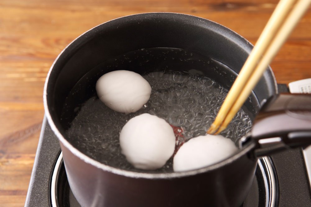 菜箸で茹でている卵を転がしているところ