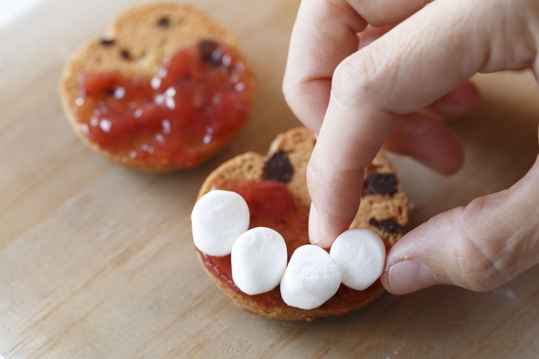 チョコチップクッキー２枚の裏面に、半分だけいちごジャムを塗る。ジャムの上に、半分に切ったマシュマロを右写真のように並べて、もう１枚ではさめばでき上がり。「無印良品のミニサイズのマシュマロが、半分に切って使うとちょうどいい大きさでした！」
さらにチョコペンなどで汚した風にするとゾンビ感がでたりするかも。