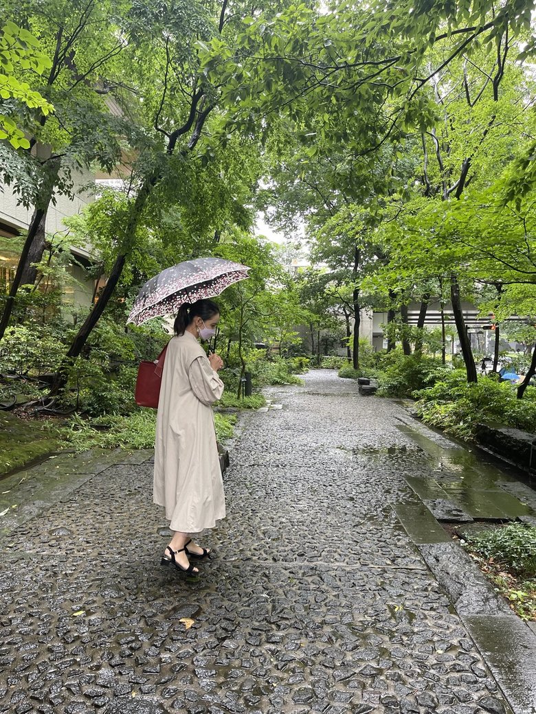 白い上着がお似合い。雨の中、傘をさして散歩する加藤さん