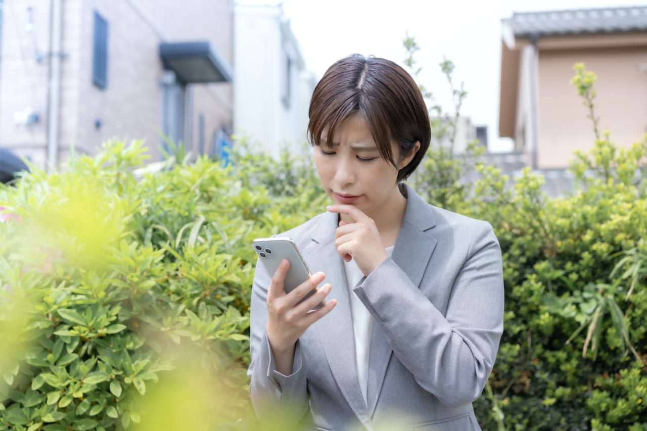 スマホを見て困惑する女性