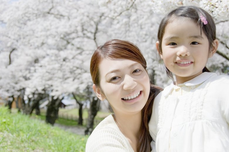 満開の桜の木を背景にする母娘