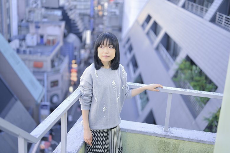 手すりに手をかけ、都会の空を見上げる川嶋さん