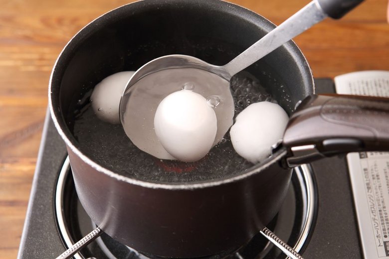 沸騰したお湯にお玉で卵を入れているところ