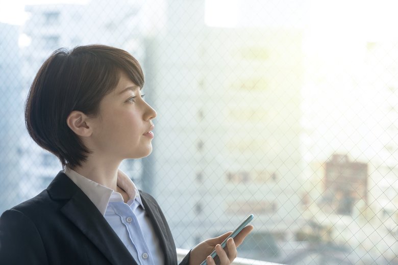 Young woman holding smart phone in the office.