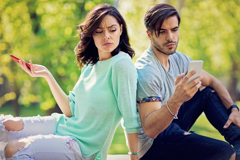 Couple in conflict is texting in the park and sulking each other