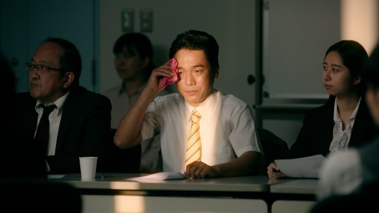 会議中、自分にだけ当たる日差しに耐えるシーン