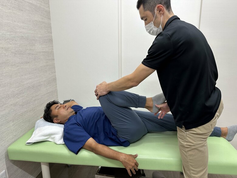 成長痛や足の痛みを防ぐストレッチ⑤仰向けに寝る。右膝を持ってもらい、曲げながら上半身に近づけ、股関節の前側を伸ばす。反対側も同様に