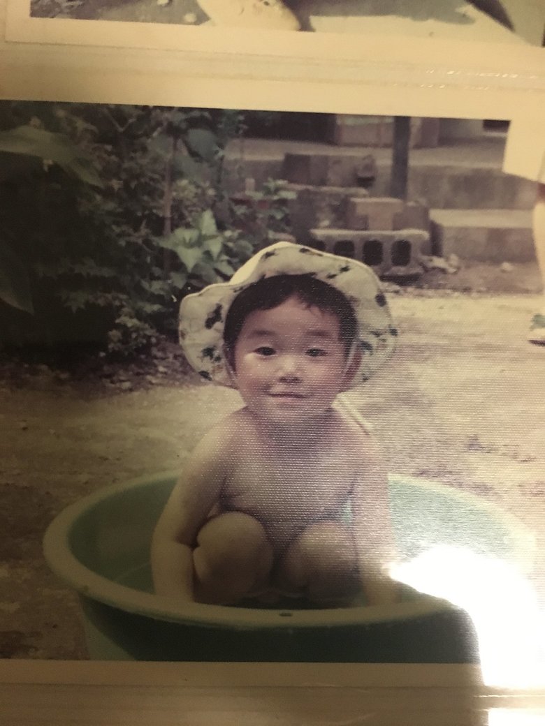 タライで水遊びをする幼少期の佐藤さん