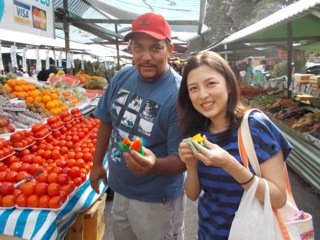 ブラジル・サンパウロの市場（フェイラ）にてお店の方と、フルーツを試食中の一枚「 フェイラは毎週通っていました！」